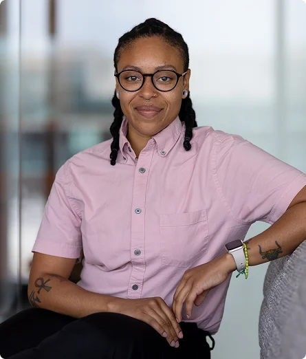 Octavia Carson wearing glasses and a pink shirt is sitting comfortably on a couch
